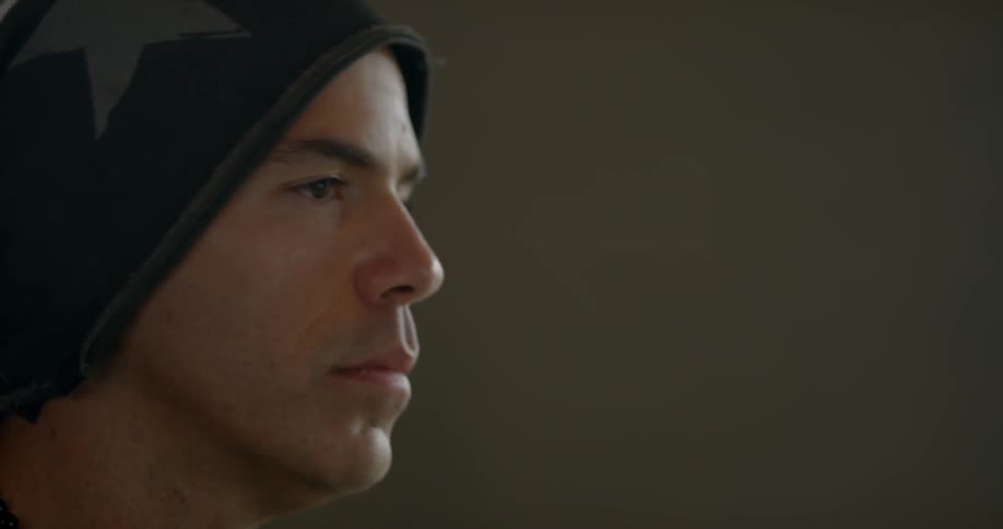 A man puts headphones on over his hat while sitting in a room