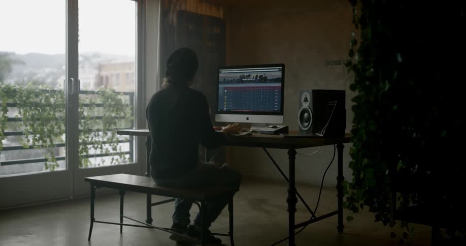 A white person sits at a table and uses a desktop computer