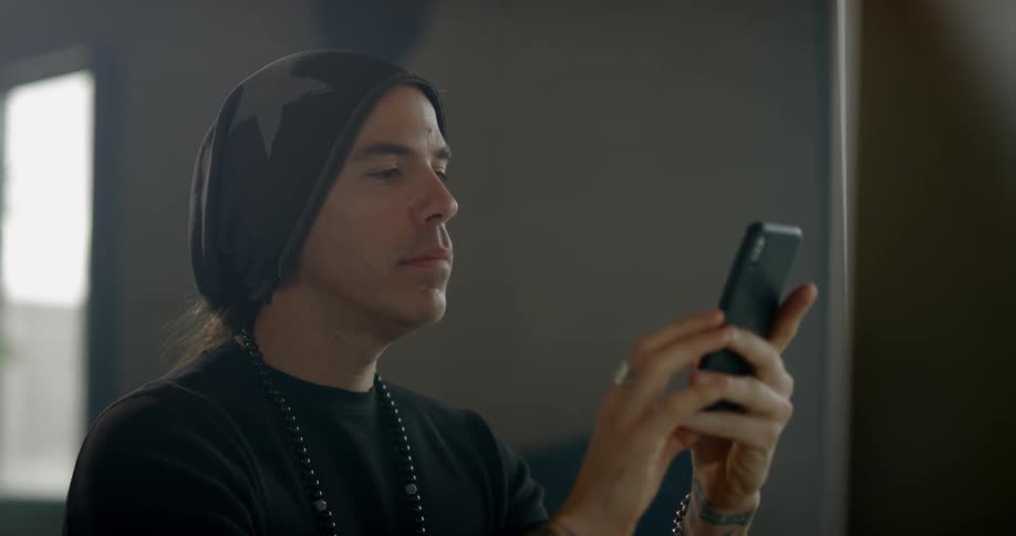 A white man fiddles with a smart phone