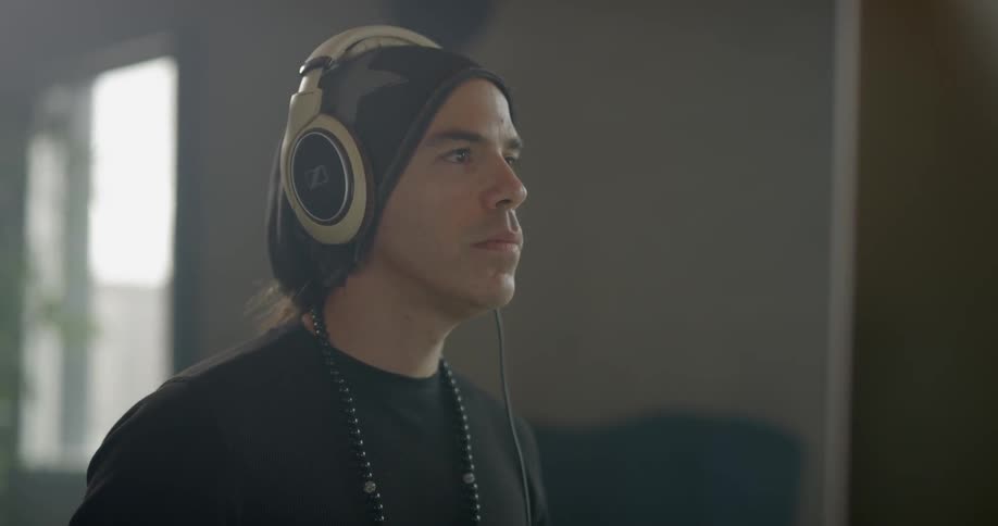 A man puts on headphones and nods at a computer screen