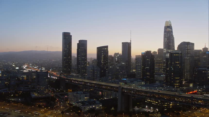 Traffic moves along two layer highway through city with mountain on horizon