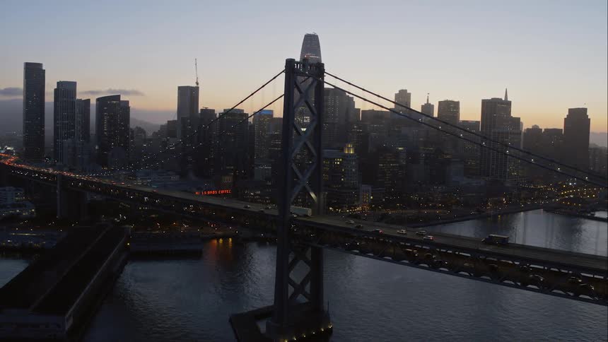 Traffic moves across a suspension bridge in a large urban area