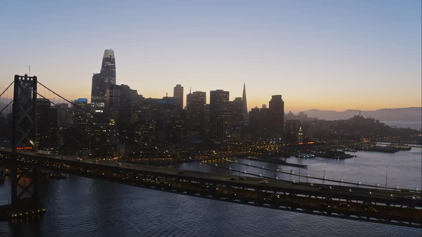 Cars drive along a city bridge at sunrise