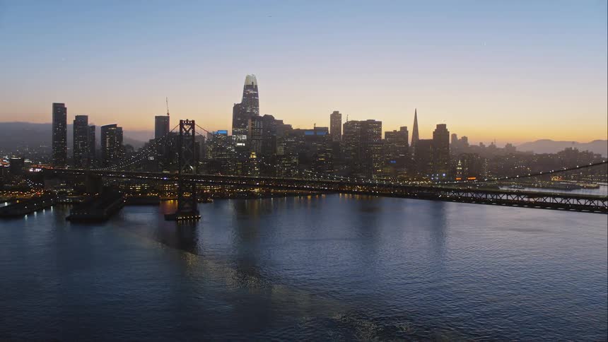 Cars drive along a city bridge at sunrise