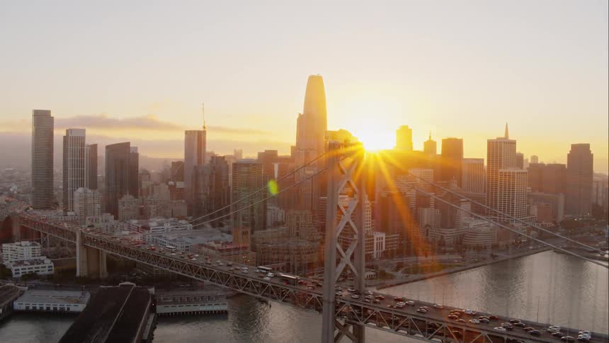 Skyline of the city next to the sea and vehicles going over the bridge at sunset