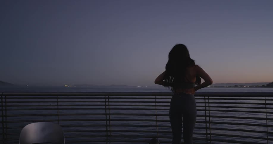 A woman stretching on a pier with a bridge in the background