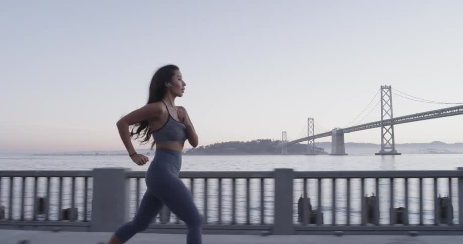 A woman runs on the bridge near the water