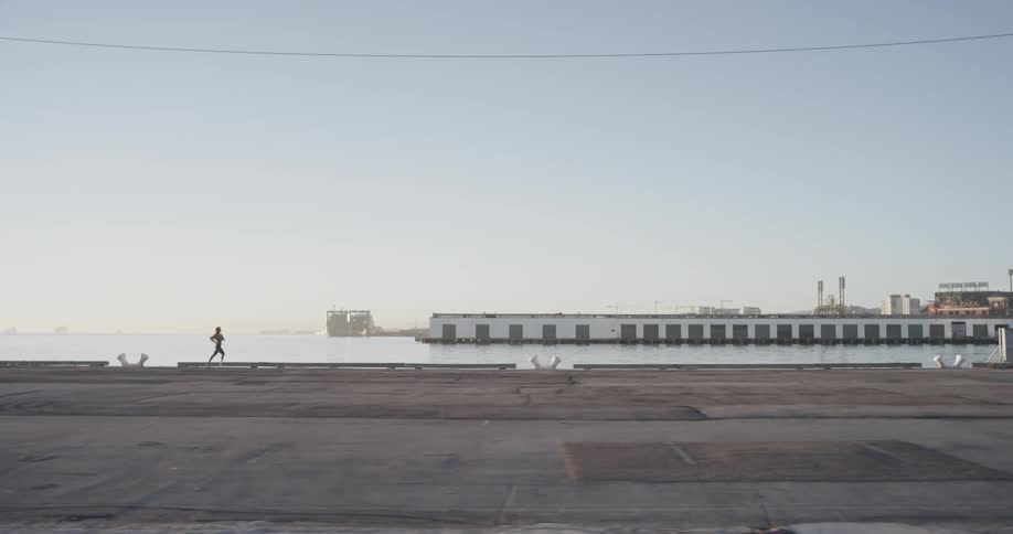 A woman runs along a pier next to the water
