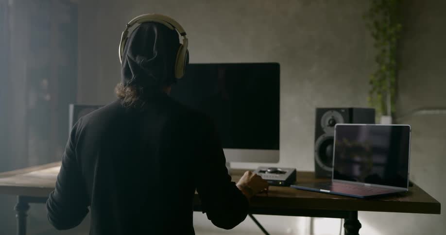 Man wearing headphonessits at the table and listen to music shaking his head during daylight