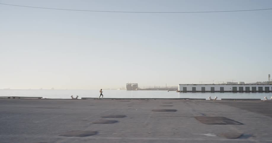 Woman runs along the promenade next to the sea during daytime