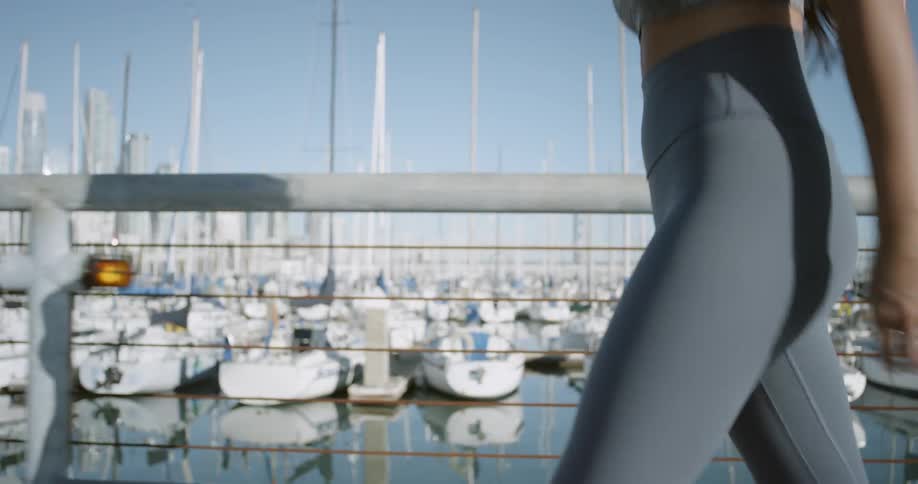 A caucasian woman walking along a pier at a marina