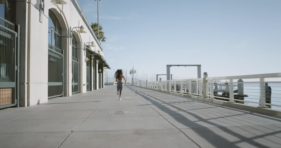 Woman runs along a seaside promenade during daylight