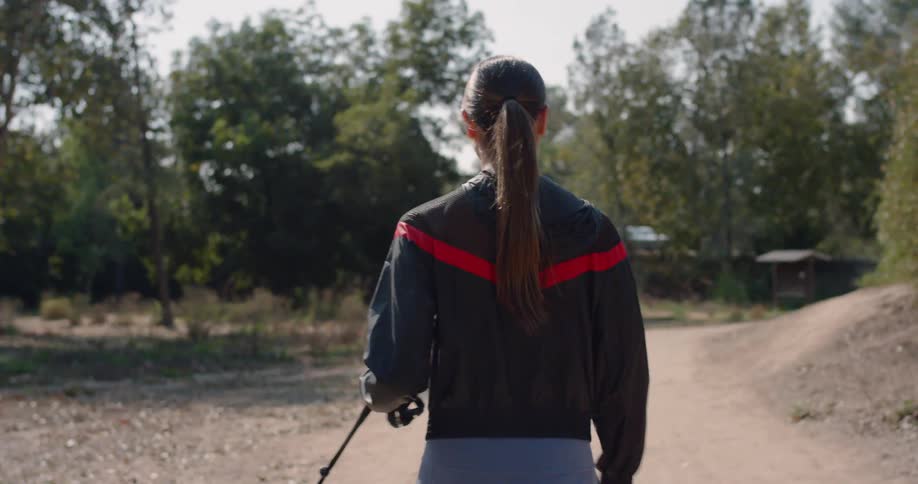 A woman walks her dog down a park pathway