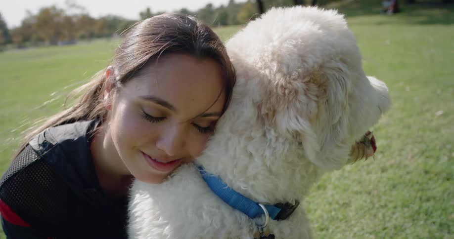 A woman hugging a white dog in a park