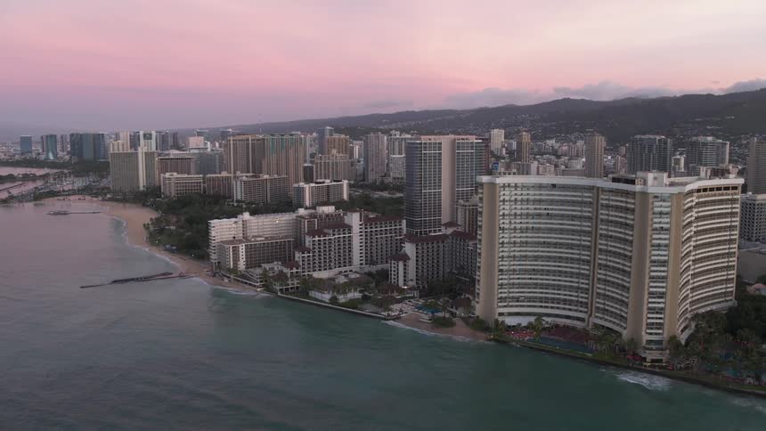 A city with towering buildings sits on a coastline