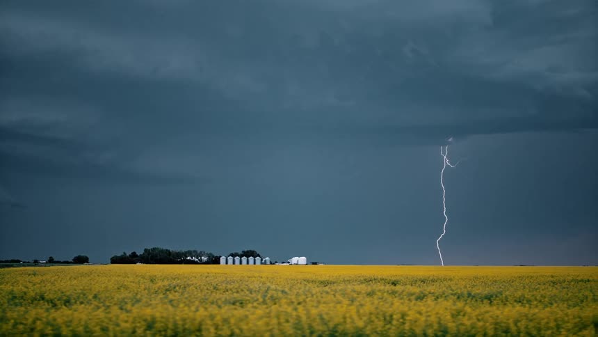 A storm with lightning sits over a farm