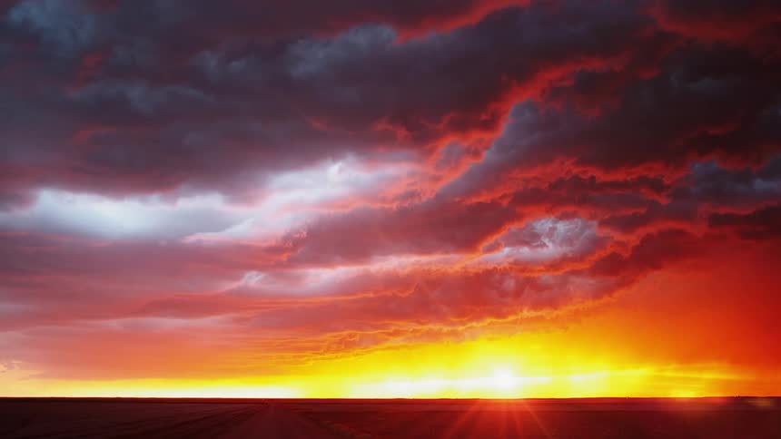 Storm clouds move by as the sun sits on the horizon