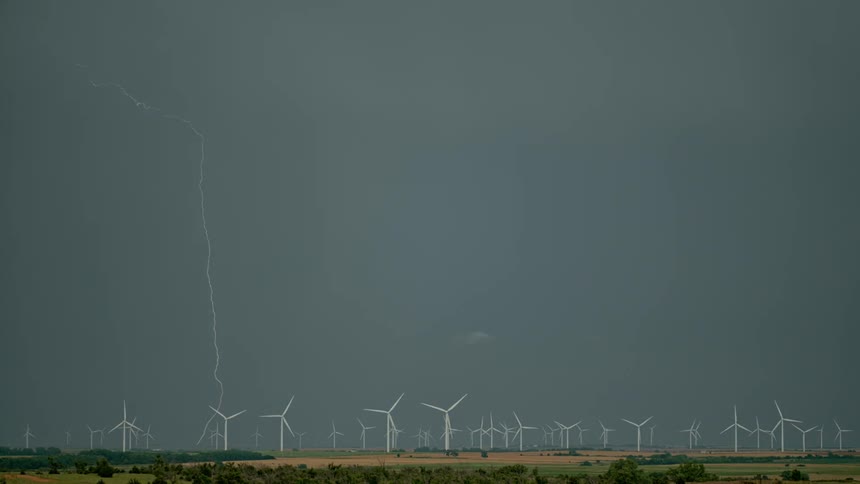 Wind turbines turn slowly as storm clouds loom overhead