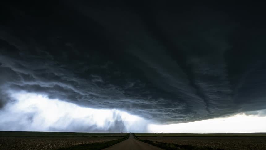 Vehicle travels down the road as dark clouds float overhead