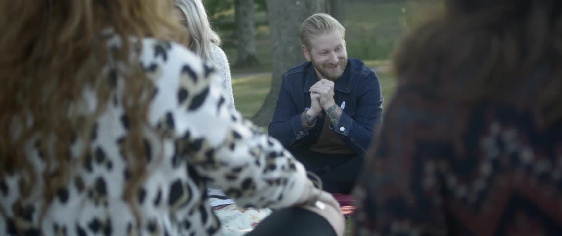 A group of people are enjoying a picnic in a park during the fall season
