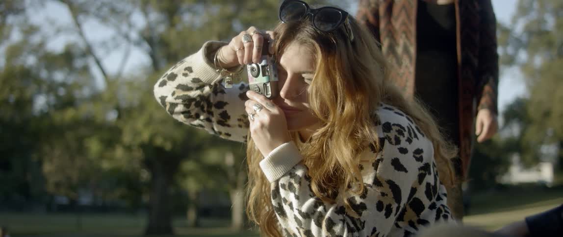 A woman takes a photograph with a camera in a park