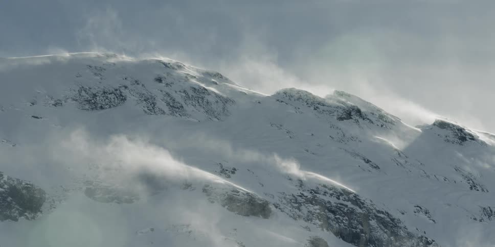 Snow plumes off of a snowy mountain