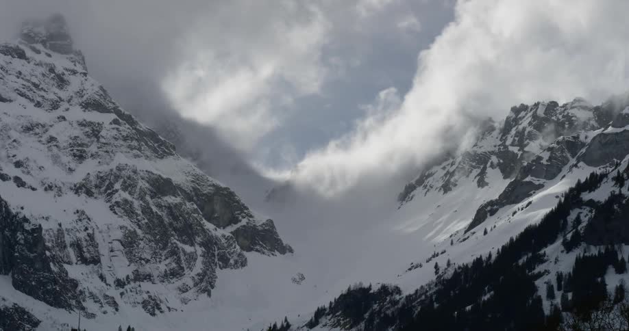 Clouds float behind a snow covered mountain range