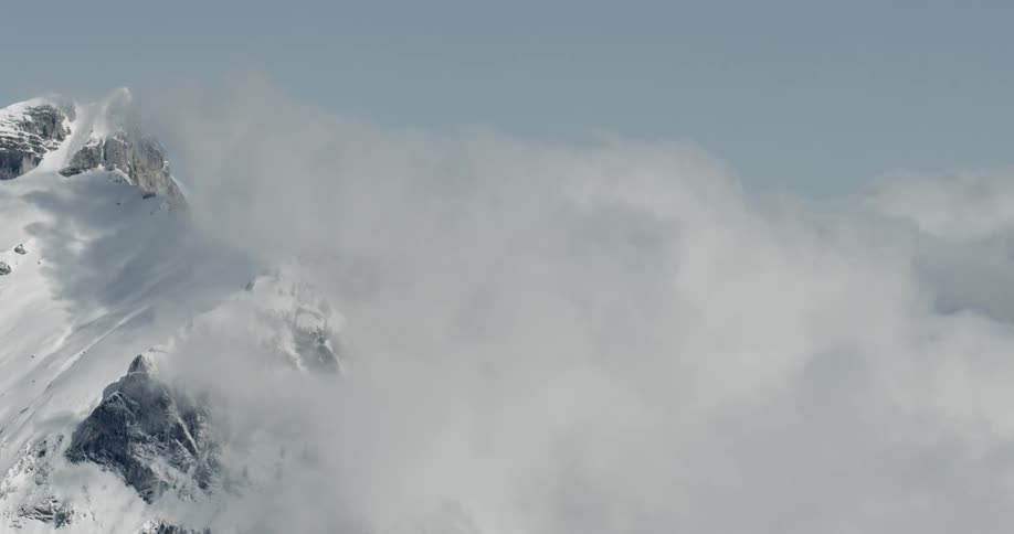A view from the top above a snow covered mountain looking into the clouds
