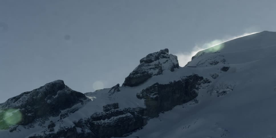 The sun starts to rise behind a snow covered mountain range