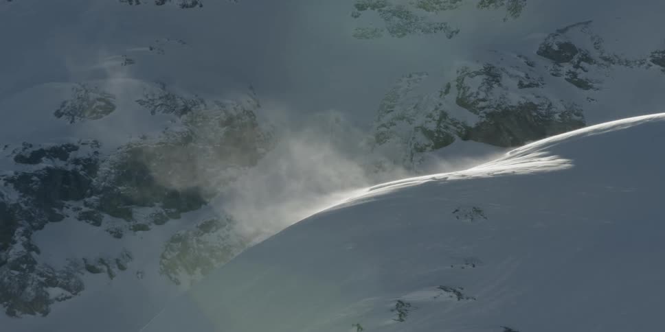 Snow is blowing off of a mountain top