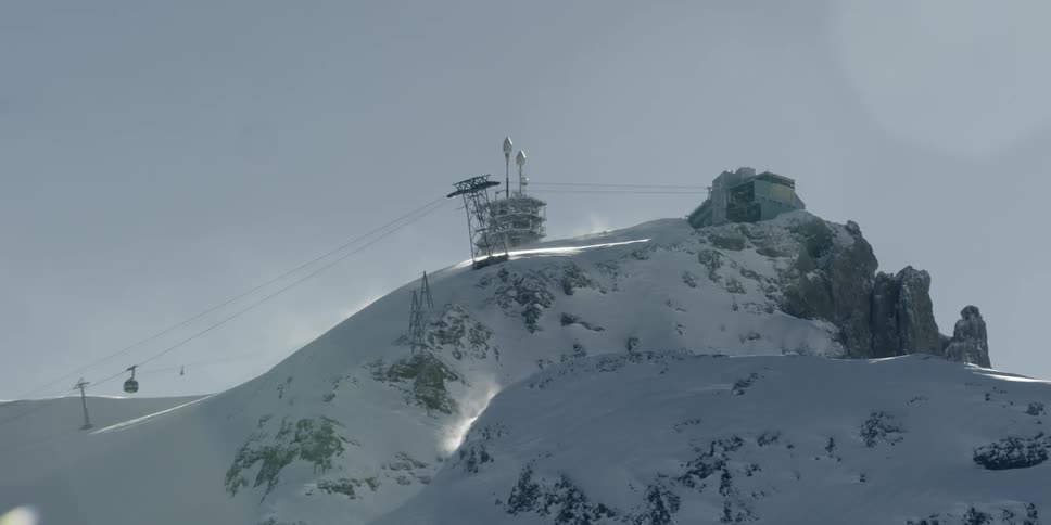 A ski lift runs down the line of the snow covered mountain