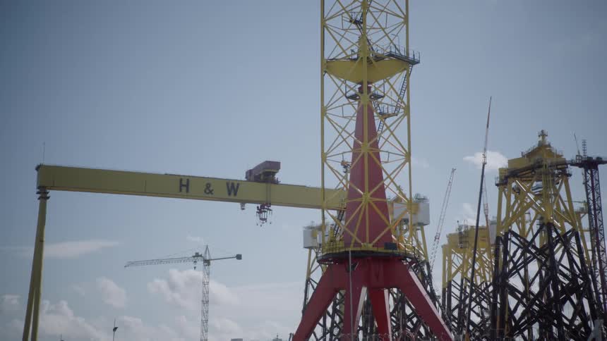 A construction crane and other equipment sits on a work site behind a fence