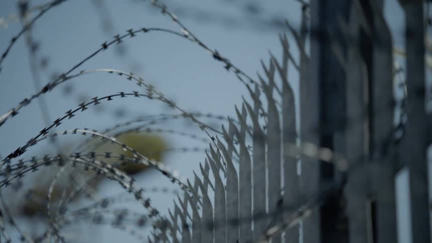 A barbed wire fence near a crane during the day