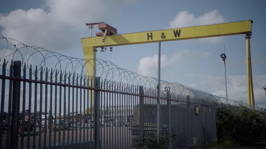 A barbed wire fence runs around a parking lot