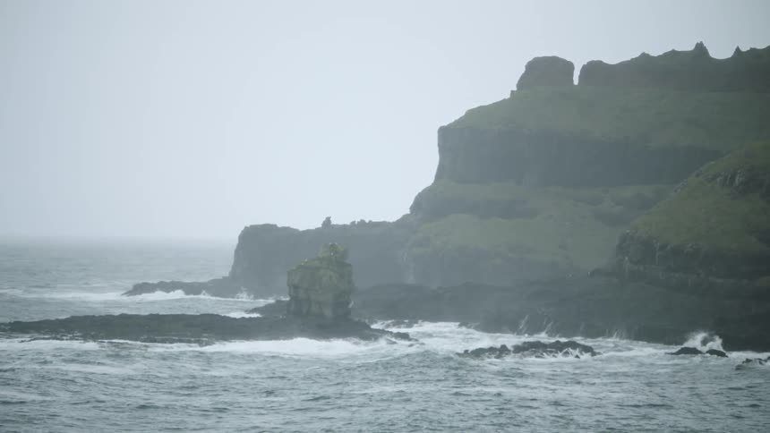 Ocean tide crashing against a headland on a foggy morning