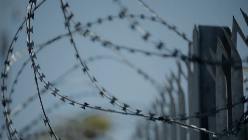 Barbed wire is covering the top of a fence