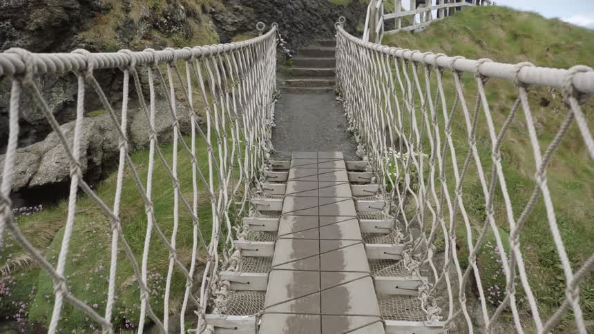A footbridge leads to stairs on a grassy cliff