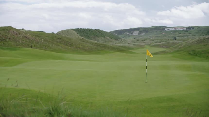 A flag waving on a golfing green during the day