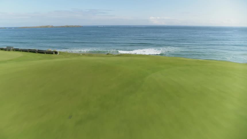 The golfing green is next to the ocean