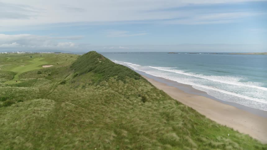 A lush green golf course edges up to the ocean