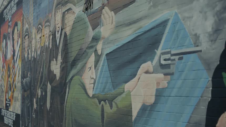 A mural of a person holding a gun painted on a brick wall