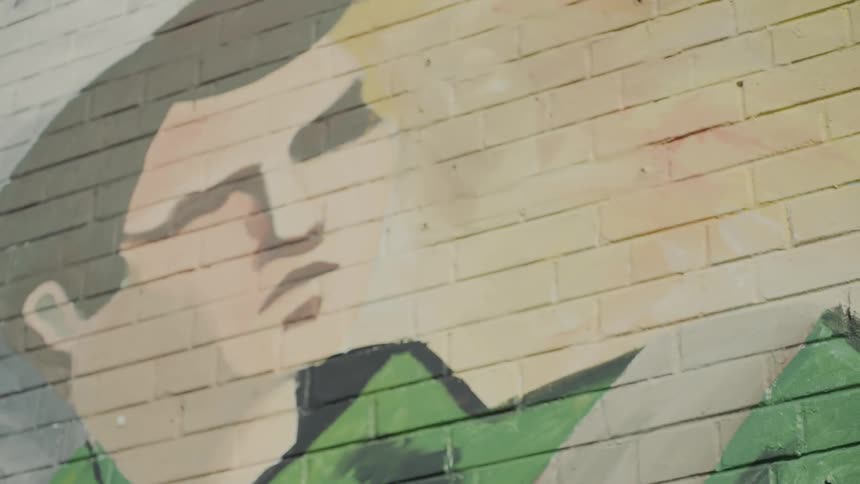 A mural of a man on a painted brick wall
