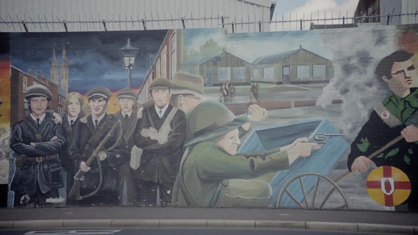 Vehicles drive past a painted wall mural
