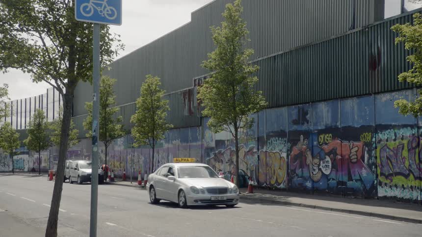 A car drives by a wall with painted murals in a city