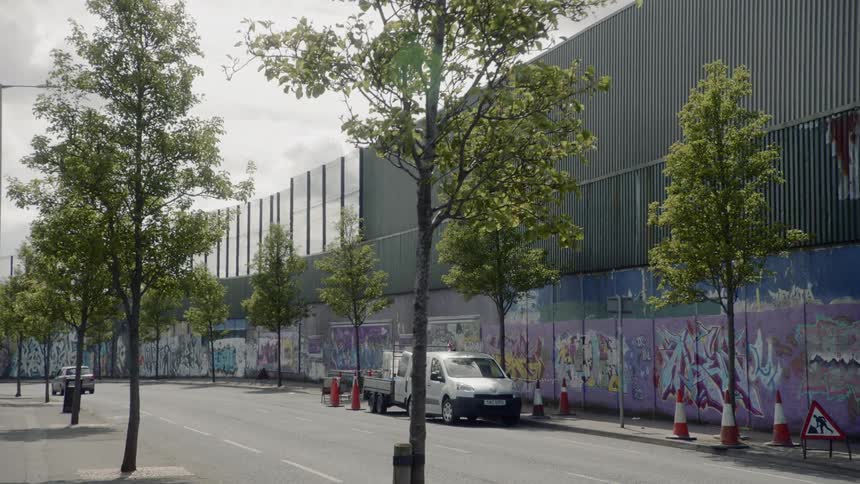 A work van is parked along the street beside a mural