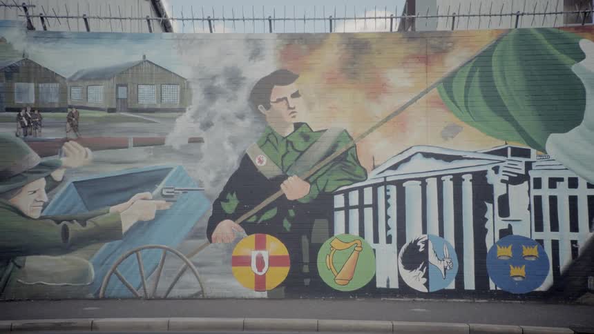 An outdoor brick wall painted with various scenes of war
