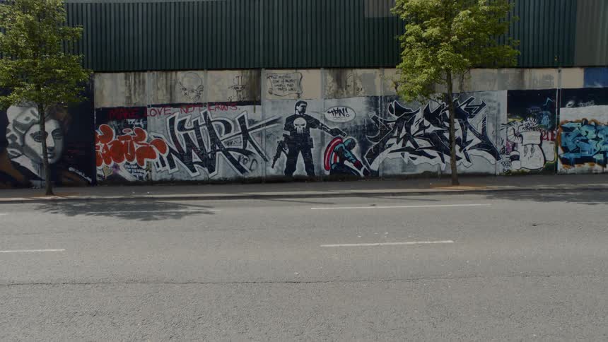 It is a street and there is graffiti of a boy with a gun