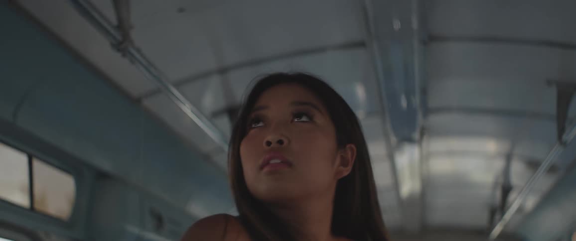 A woman stands up in a bus and looks at the ceiling
