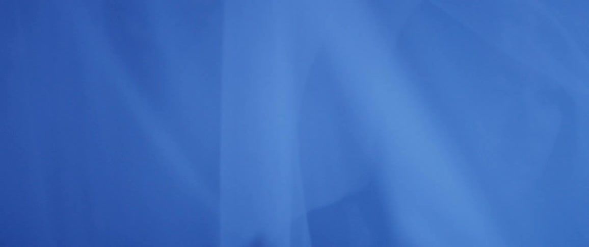 Women walk through and push aside sheer fabric in a blue light