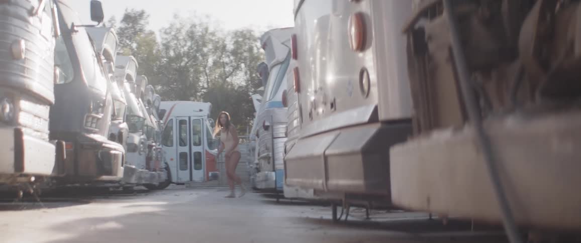 A woman in leotard walking carefully through a bus yard